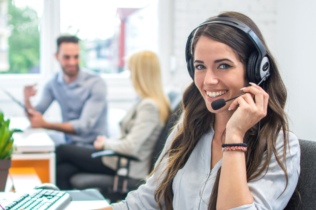 Portrait of happy smiling female customer support phone operator at workplace.