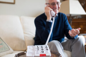 senior man using telephone with oversize keypad at home
