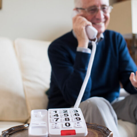 Senior Man Using Telephone With Oversized Keypad At Home
