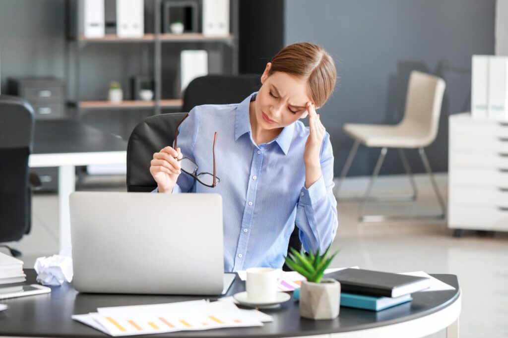 Young woman suffering from headache in office